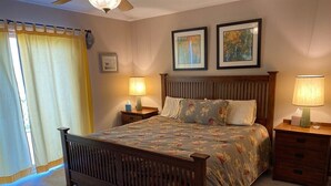 Une chambre à coucher avec un lit en bois, deux tables de chevet avec des lampes, une tête de lit et deux tableaux encadrés accrochés au mur.