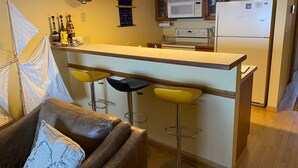 Une cuisine compacte avec un coin bar, des meubles en bois, un four à micro-ondes et un réfrigérateur.