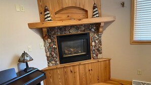 Une pièce avec une cheminée, des étagères en bois et un piano.