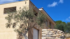 Un edificio moderno con un muro de piedra, una ventana y un árbol en primer plano.