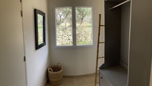 Una habitación con un ventanal grande, un armario, una cesta de mimbre y una escalera.