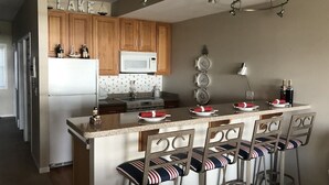Una cocina con armarios de madera, un microondas, una estufa y una barra con taburetes.