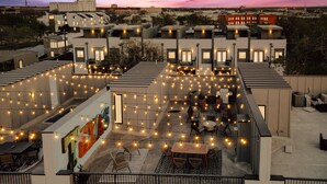 A rooftop terrace with string lights, outdoor seating, and a view of the surrounding buildings.