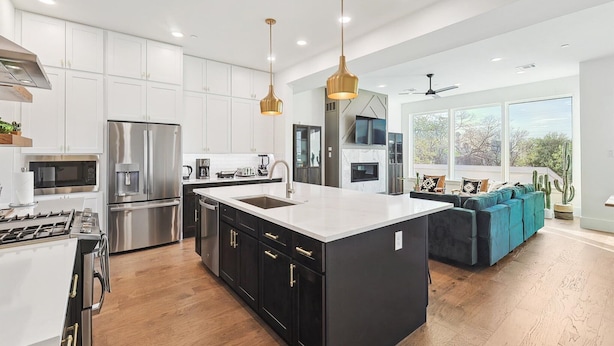 A modern kitchen with a central island, stainless steel appliances, and pendant lighting.