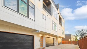 A modern two-story building with large windows, a balcony, and a garage.