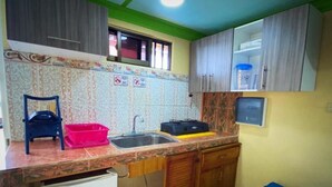 Una cucina compatta con lavandino, un piccolo frigorifero e un forno a microonde. Nella stanza c'è una sedia e un letto blu.