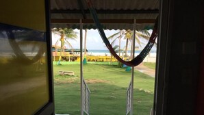 Vista da una stanza con un’amaca, un patio e una spiaggia sullo sfondo.