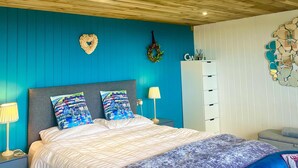 A bedroom with a bed, bedside tables, a wardrobe, and a decorative wall piece. - The Pod Luxury Accommodation (Aberaeron)