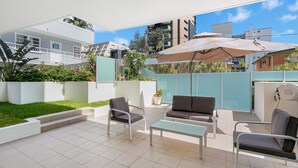 A patio with outdoor furniture, a large umbrella, and a view of the surrounding buildings.