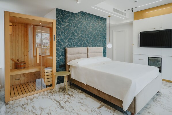 A modern bedroom with a large bed, a wooden wardrobe, a small table, a TV, and a wall with a leaf pattern. - POETICA BOUTIQUE SKY HOTEL (Naples)