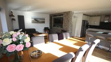 A dining area with a wooden table, chairs, a vase of flowers, and a stone accent wall.