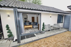 A modern house with a patio area featuring a sofa, chairs, and a dining table.