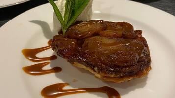 A dessert plate with caramelized fruit on top, garnished with mint leaves and drizzled with caramel sauce.
