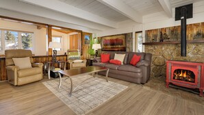 A cozy living room with a stone fireplace, leather furniture, and a large window. - 45 Idlewild New 2 bedroom private home private hot tub, walk to downtown (Winter Park)