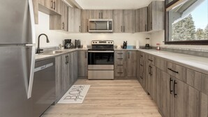 A modern kitchen with wooden cabinets, stainless steel appliances, and a large window. - 45 Idlewild New 2 bedroom private home private hot tub, walk to downtown (Winter Park)