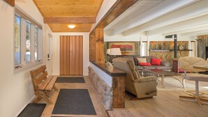 A cozy living area with a stone fireplace, a wooden bench, and a sofa with cushions. - 45 Idlewild New 2 bedroom private home private hot tub, walk to downtown (Winter Park)