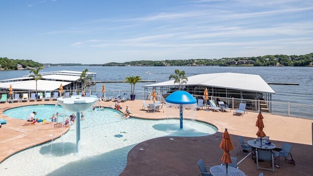 A pool area with a water feature, lounge chairs, umbrellas, and a view of the water.