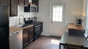 A modern kitchen with dark wood cabinets, stainless steel appliances, and a white tiled backsplash. - The Modern beach bungalow. 7 minutes to ocean front, full private home!  (Virginia Beach)
