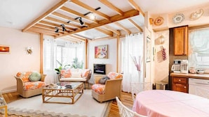 A cozy living room with wooden beams, wicker furniture, and a television. - The Golden Suite: themed getaway! (Cincinnati)