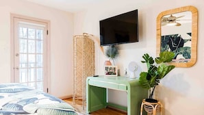 A bedroom with a bed, a green desk, a television, a mirror, and a potted plant. - The Golden Suite: themed getaway! (Cincinnati)