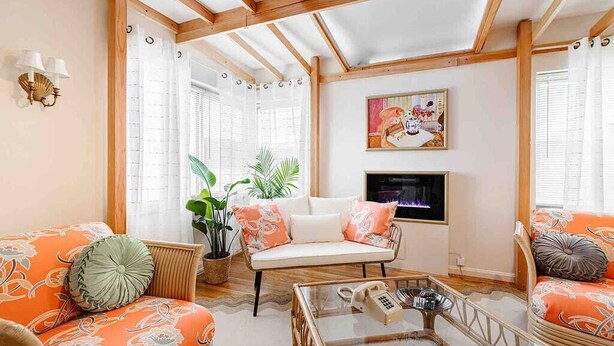 A living room with a sofa, armchair, and coffee table, a fireplace, and a large window with curtains. - The Golden Suite: themed getaway! (Cincinnati)