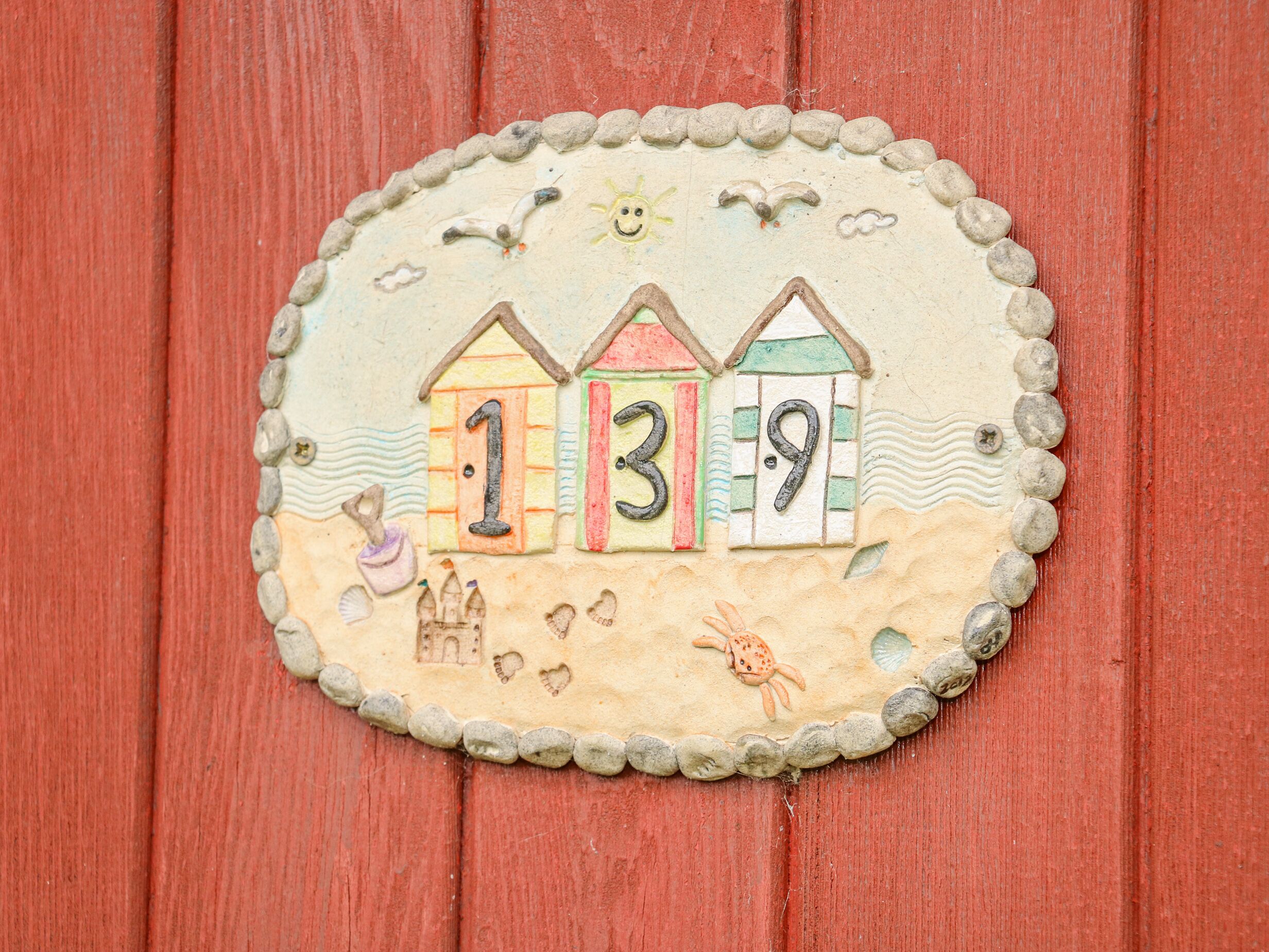 Segno decorativo a tema spiaggia con i numeri 1, 3 e 9, un sole e un granchio.