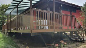 Eine Holzterrasse mit Metallgeländer, eine Treppe und ein rotes Gebäude im Hintergrund.