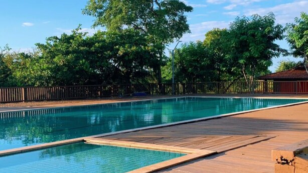 Ein Schwimmbad mit Holzterrasse und einem Zaun.