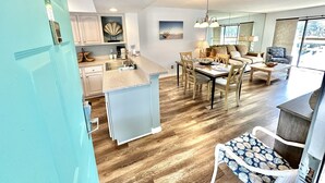 Une cuisine moderne avec un coin repas, un plancher en bois et une vue sur l’extérieur.