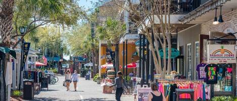 Une rue bordée de boutiques et de cafés, où l’on peut voir des piétons se promener.