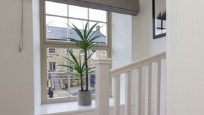 A staircase with a white railing leading to a window. A potted plant is placed on the windowsill. - Millnook (Harrogate)