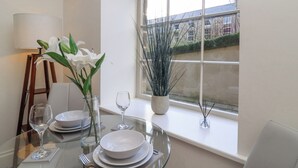 A dining table set with plates, a wine glass, and a vase with white flowers. - Millnook (Harrogate)