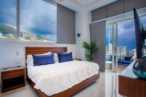Ein modernes Schlafzimmer mit einem großen Bett, einem Nachttisch, einer Topfpflanze und Blick auf die Stadt durch ein großes Fenster.