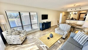 A living room with a sofa, armchair, coffee table, and a TV on a stand. - New Rental, Beautiful villa with relaxing views! 912HP (Miramar Beach)