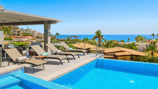 Une piscine avec des chaises longues et vue sur l’océan.