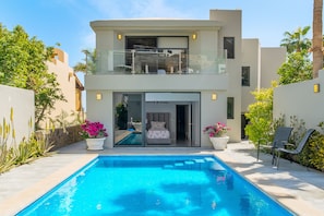 Una casa moderna de dos pisos con piscina, balcón y jardín.