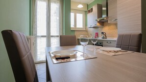 A dining area with a table set for two, a kitchen in the background, and a window with curtains. - Modern Apartment in Santa Rita by Wonderful Italy (Torino)