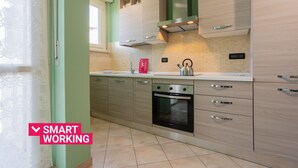 A modern kitchen with light wood cabinets, a stainless steel oven, and a kettle on the counter. - Modern Apartment in Santa Rita by Wonderful Italy (Torino)