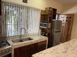 Una cocina con estufa a gas, pileta doble, gabinetes de madera y encimera de mármol.