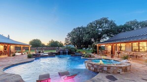 A swimming pool with a hot tub, lounge chairs, and a waterfall feature. - Bent Oak Highland Ranch | Events | Concierge Services (Burnet)