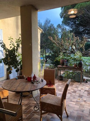 Relax in a serene outdoor space surrounded by lush greenery and trees, featuring a round table and two comfortable chairs.