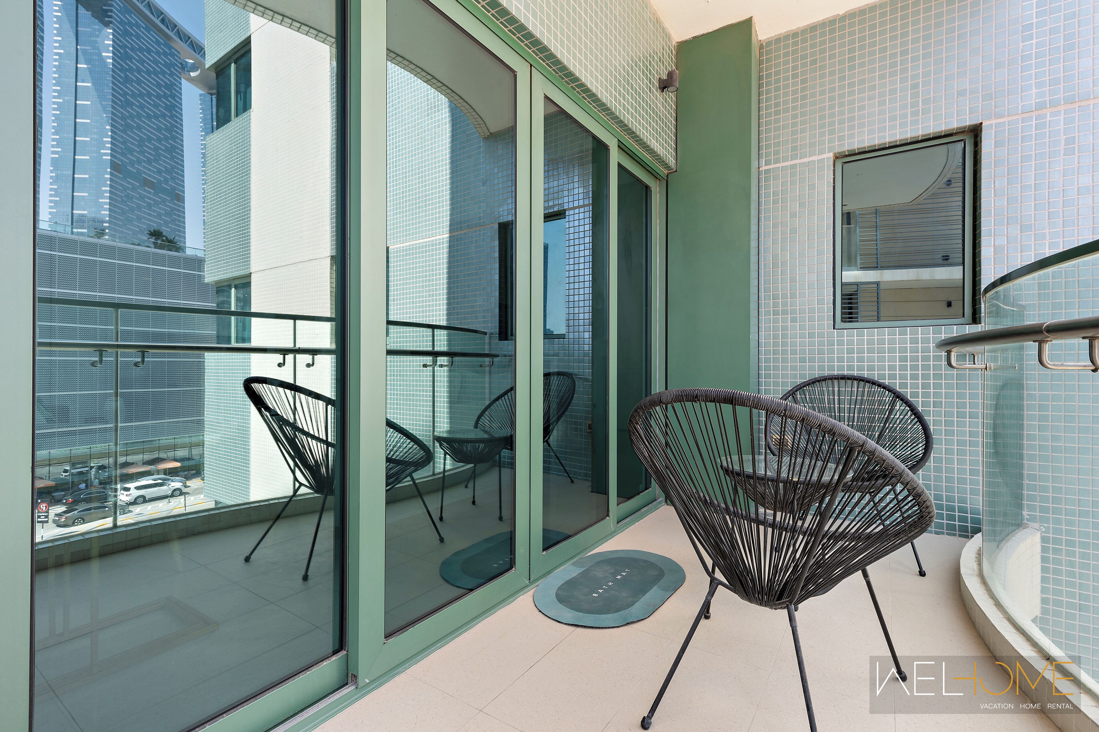 A balcony with glass doors, two wicker chairs, and a small table.