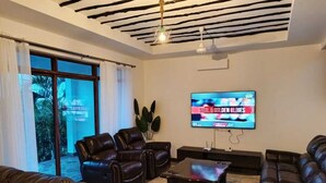 Un saló modern amb sofàs de pell, televisió de pantalla plana i sostre amb bigues al descobert.