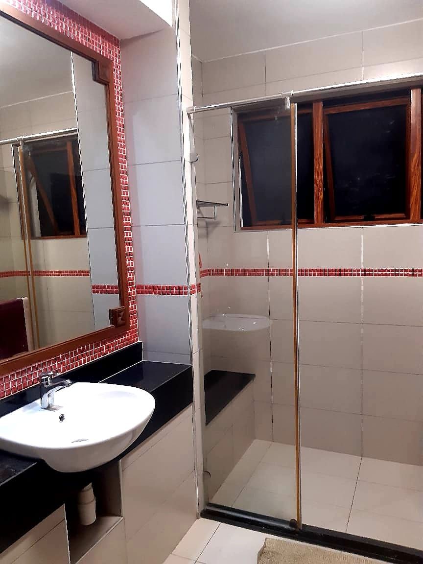 Un baño con un lavamanos blanco, un espejo y una cabina de ducha de vidrio.