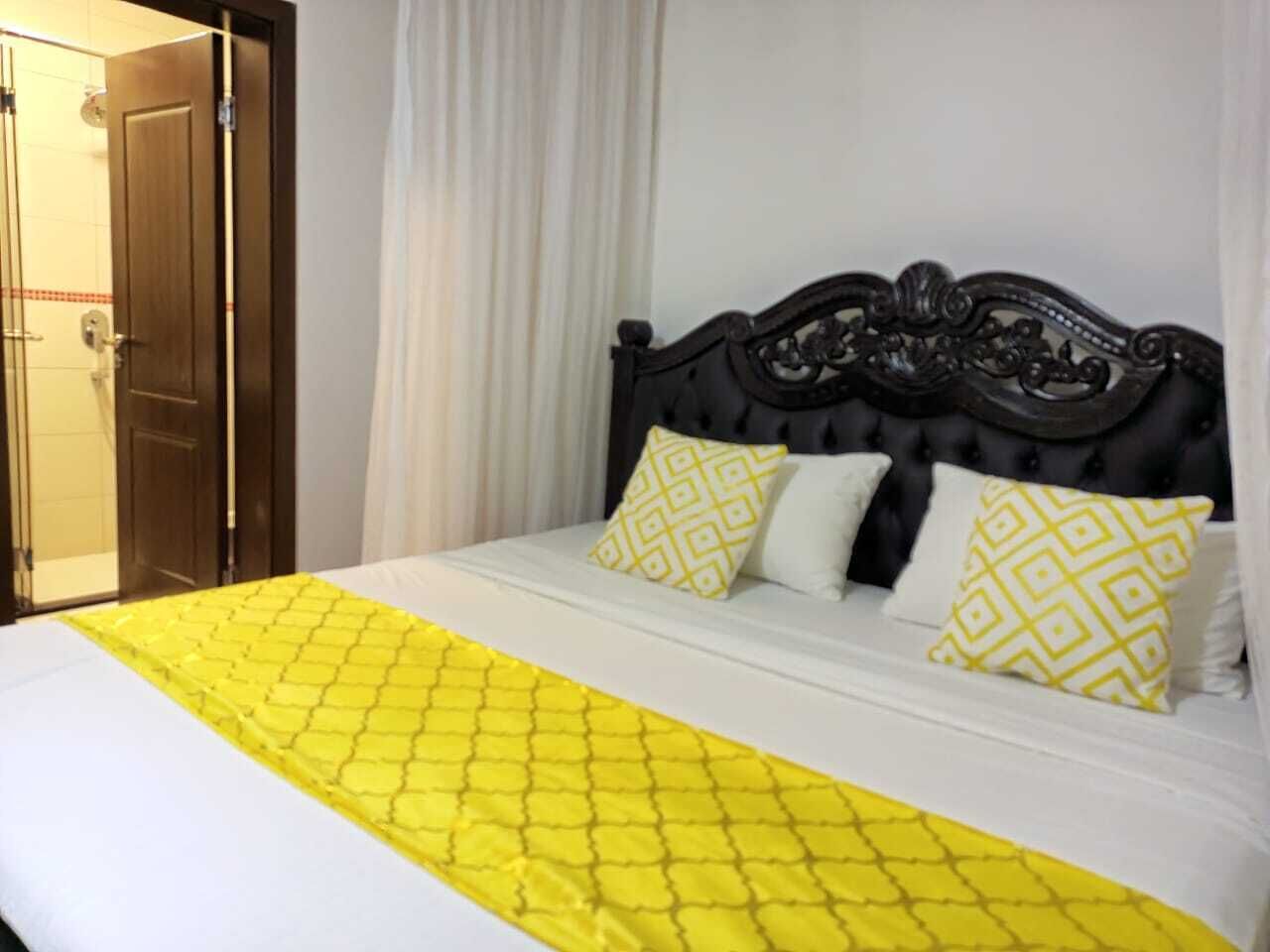 Une chambre d’hôtel avec un lit, une porte en bois et un rideau blanc.