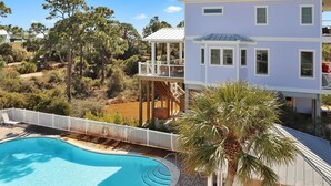 Ein zweigeschossiges Haus mit Swimmingpool, umgeben von Bäumen und blauem Himmel.