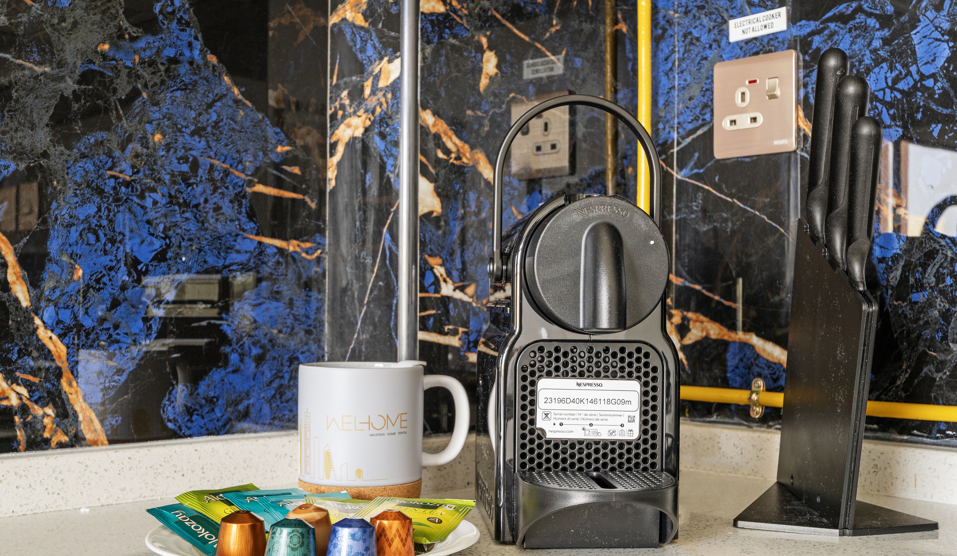 A coffee maker, a mug, and coffee pods on a countertop with a marble backsplash.