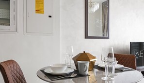 A dining table set with plates, bowls, glasses, and cutlery, with a chair and a decorative basket.