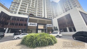 A modern hotel with a prominent 'Jewelz' sign, surrounded by high-rise buildings and parked cars. - WelHome - Cozy Studio Apt. with Private Balcony in Arjan (Dubai)