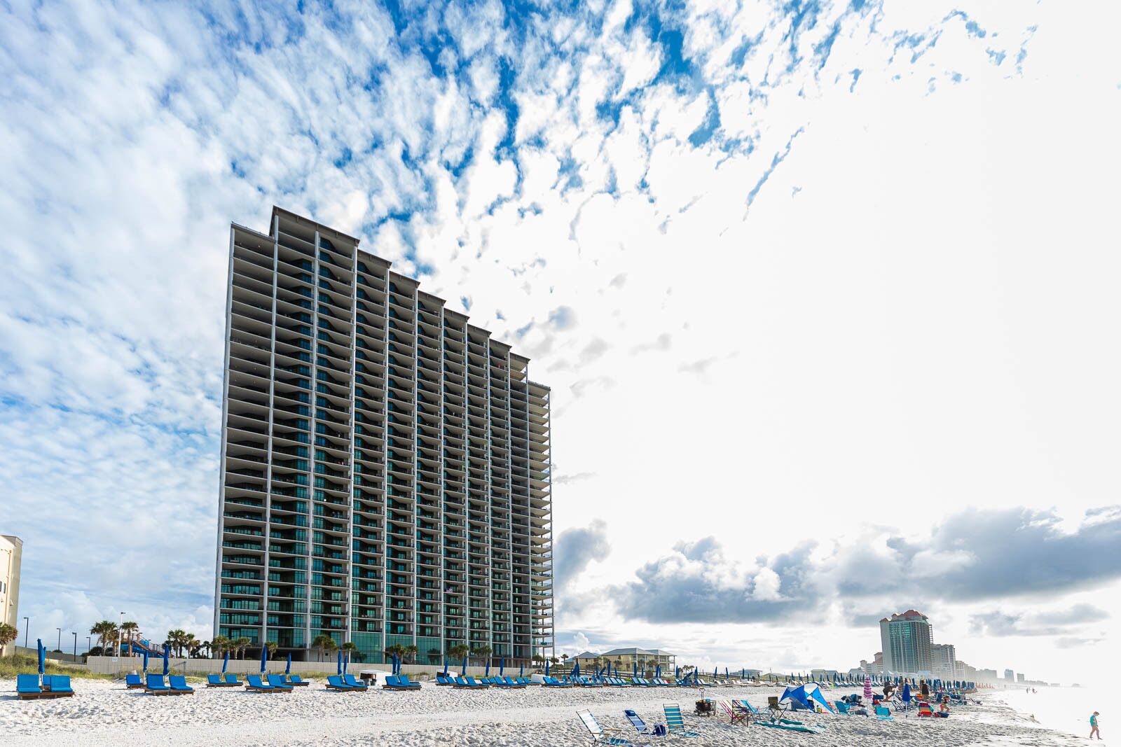 A high-rise hotel with a modern design, featuring a large number of balconies and a prominent glass facade.